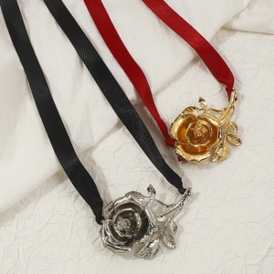 Gedetailleerde weergave van gelaagde metalen roosbroches met satijnen linten in goud en zilver