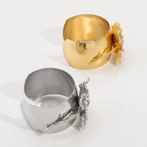 Detailopname van sculpturale metalen bloemen op gepolijste gouden en zilveren armbanden