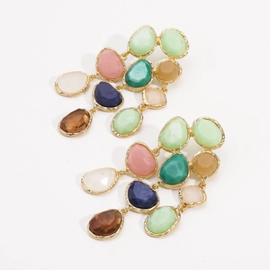 Macro shot of colorful resin drop earrings with gold metal edges in bohemian style