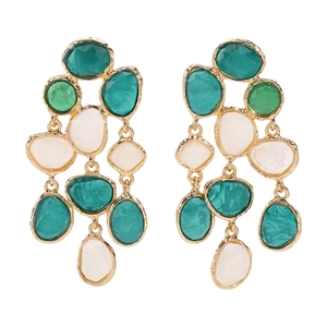 Close-up of bohemian tassel earrings with green resin stones and hammered gold frames