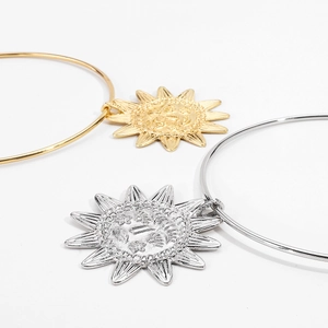 Détail des bracelets en or et argent avec des pendentifs en forme de soleil en relief