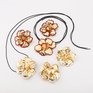 Detail van vintage gouden bloemhangers met rode en witte emaille randen