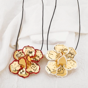 Detailweergave van grote gouden bloemenhangers met rode en witte emaille randen