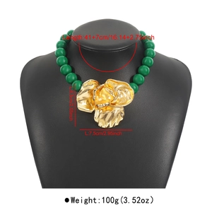 Detail of green beaded necklace with large gold flower pendant and size specifications