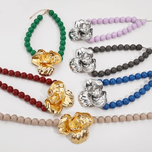 Close-up of vibrant beaded necklaces with large metallic flower pendants and lobster clasps