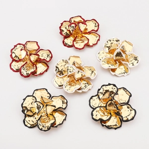 Detailopname van gouden bloemhangers met gekleurde emaille randen in rood wit en zwart