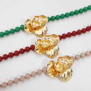 Close-up of beaded necklaces featuring large golden 3D rose pendants in multiple colors