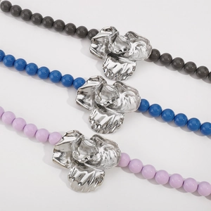 Detailed macro view of colorful beaded necklaces featuring artistic silver flower pendants