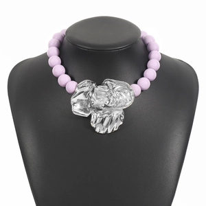 Statement necklace with purple beads and oversized silver flower pendant on a black bust