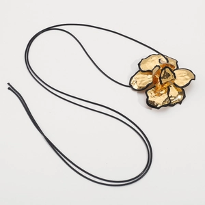 Gedetailleerde weergave van een grote gouden bloemhanger met reliëf en zwarte randen