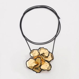 Detail van een gouden metalen bloem hanger met zwarte randen en gelaagde blaadjes