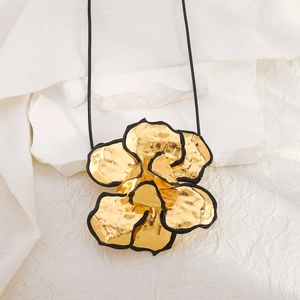 Macro-opname van 3D gouden bloem hanger met zwarte randen op witte getextureerde stof
