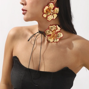 Gouden bloemenoorbellen en choker set met rode details op een vrouwelijk model