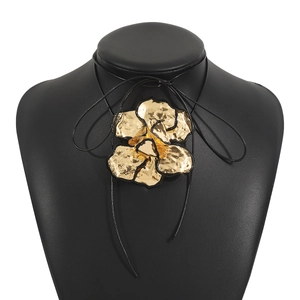 Detail van een gouden bloemenhanger met zwarte rand aan een zwarte koordketting