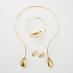 Vista detallada del conjunto de joyas doradas pulidas con collar, brazalete y pendientes