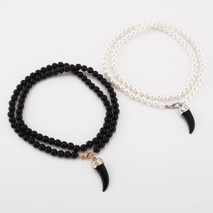 Detail of layered pearl and black bead necklaces with wolf tooth pendant accents