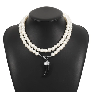 Double-layer pearl necklace with vintage wolf tooth pendant on a black mannequin bust