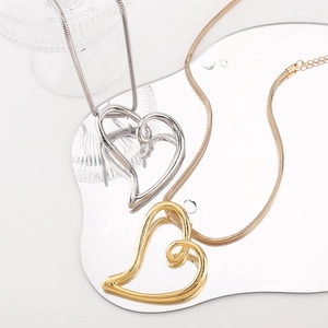 Détail des pendentifs cœur dorés et argentés sur chaînes serpent avec reflets de miroir