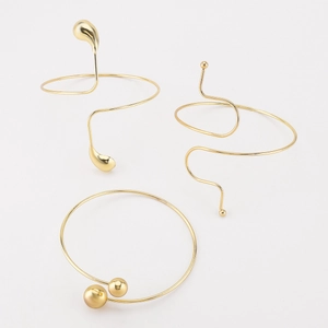 Détail de trois bracelets spirale dorés irréguliers avec extrémités goutte et perle