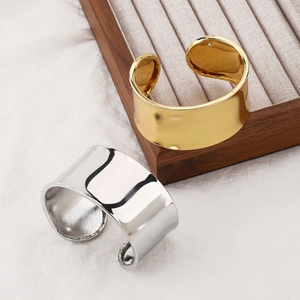 Bracciali larghi aperti in oro e argento lucido su vassoio per gioielli in legno