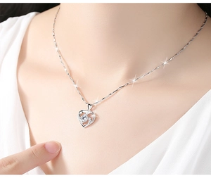 Gros plan d'un collier cœur avec saphir central sur la clavicule d'une femme