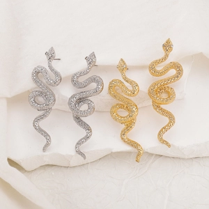 Detailed view of snake-shaped drop earrings with hammered texture and crystal eyes