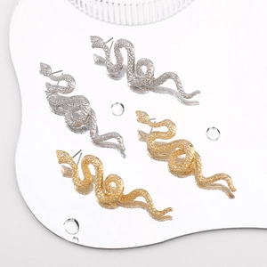 Close-up of gold and silver snake earrings with scale textures and small diamonds