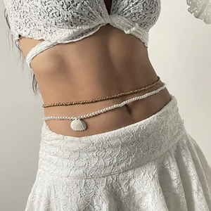 Detalle de cadena de cuerpo playera con perlas de imitación y colgante de concha blanca