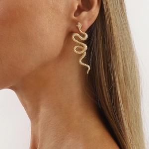 Elegant gold snake earrings with diamond accents worn by a model against white background