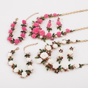 Vista plana de conjuntos de joyas florales rosas y blancas con perlas y rosas