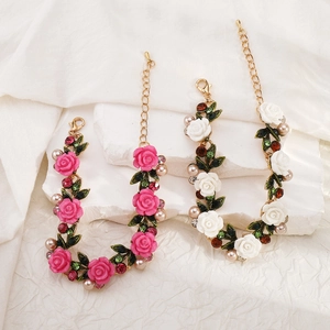 Vista de pulseras florales con rosas rosas y blancas, cristales verdes y perlas finas