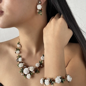 Conjunto floral con rosas blancas, hojas de esmalte verde y perlas en una modelo