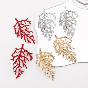 Detailed macro shot of coral-inspired branch earrings in red, gold, and silver finishes