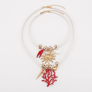 Dettaglio della collana boho a strati con corallo rosso, sole dorato e ciondoli a conchiglia