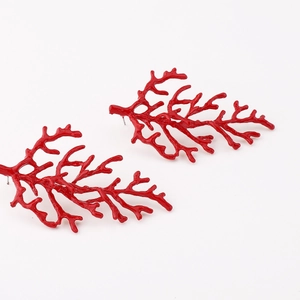 Detailed view of red coral branch earrings with polished finish on white background