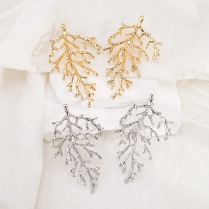 Detail of coral-shaped metal earrings in gold and silver finish on artistic stone stand
