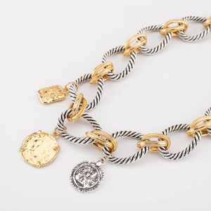 Close-up of mixed metal twisted chain with gold flower and silver coin pendants
