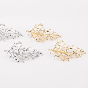 Detailed view of branch-inspired coral earrings in hammered gold and silver finishes