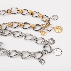 Macro shot of two-tone cable chain featuring vintage coin pendants and detailed square tags