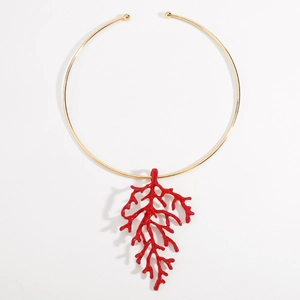 Macro detail of a gold choker necklace with a vibrant red coral branch pendant