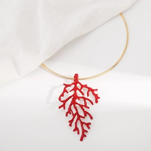 Detail of red coral branch pendant necklace with golden choker on white linen background