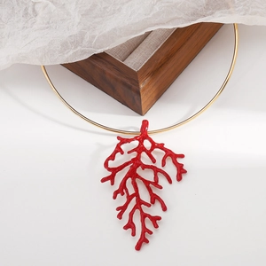 Detail of red coral branch pendant on a slim gold choker against a soft background