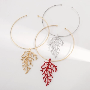 Detailed view of three coral branch chokers in gold, silver and red lacquer finish