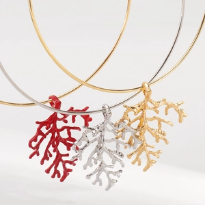Three coral branch style pendant necklaces in red, gold, and silver on sleek metal collars