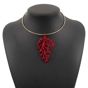 Detail view of bold gold metal choker with oversized red coral branch pendant design
