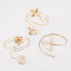 Detailed close-up of three gold adjustable upper arm cuffs with leaf, flower, and butterfly designs
