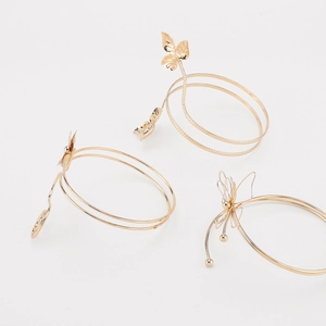Detail view of adjustable gold butterfly arm cuffs with intricate metal wire textures