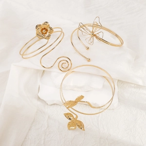 Detailed macro of golden flower and butterfly adjustable arm rings in a three-piece set
