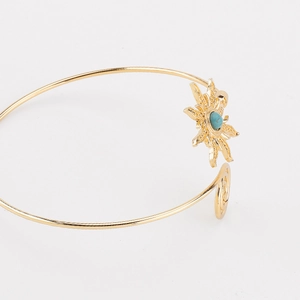 Detail van gouden armband met zonnebloem-turkoois en spiraalvormige uiteinden