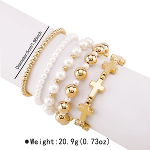 Detail view of five-piece stretch bracelet set with gold cross charms and pearls